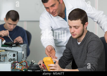 Teacher explaining multimeter to apprentice Stock Photo