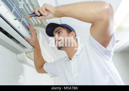 portrait of mid-adult male technician repairing air conditioner Stock Photo
