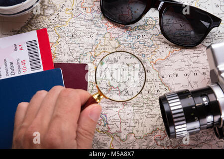 Boarding Pass Ticket And Camera With Human Hand Looking At Map With Magnifying Glass Stock Photo