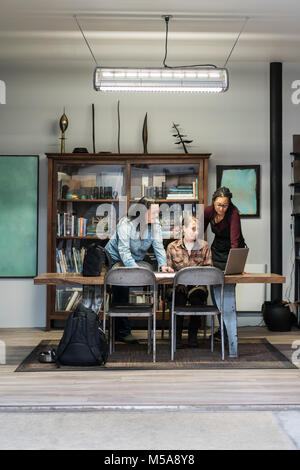 Three women gathered around table in office area of a metal workshop. Stock Photo