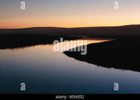 The open spaces of marshland and water channels. Flat calm water.  Dusk. Stock Photo