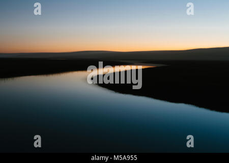 The open spaces of marshland and water channels. Flat calm water.  Dusk. Stock Photo