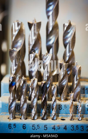 Close up of metal drill bits in a workshop sorted in size order and covered in dust. Stock Photo