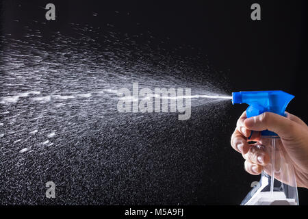 Human Hand Spraying Water With Spray Bottle On Black Background Stock Photo