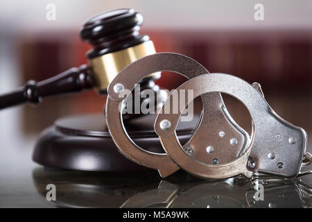 Close-up Of Handcuffs And Gavel In Courtroom Stock Photo