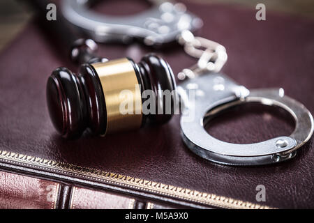 Close-up Of Handcuffs And Gavel On Law Book In Courtroom Stock Photo