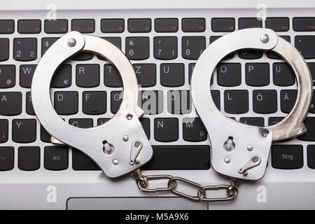 High Angle View Of Handcuffs On Laptop Keyboard Stock Photo