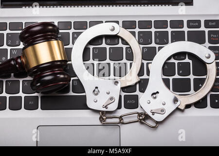 High Angle View Of Handcuffs And Gavel On Laptop Keyboard Stock Photo