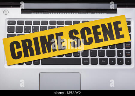 High Angle View Of Yellow Crime Scene Tape On Laptop Keypad Stock Photo