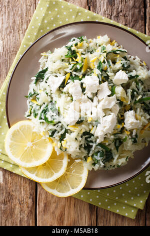 Greek cuisine: spanakorizo rice with spinach and feta cheese on a plate close-up. Vertical top view from above Stock Photo