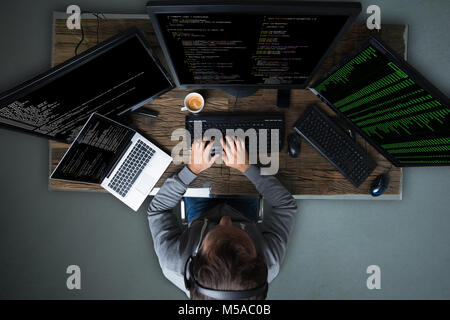 High Angle View Of Hacker Hacking Multiple Computers On Desk Stock Photo