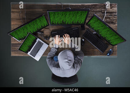 High Angle View Of Hacker Hacking Multiple Computers On Desk Stock Photo