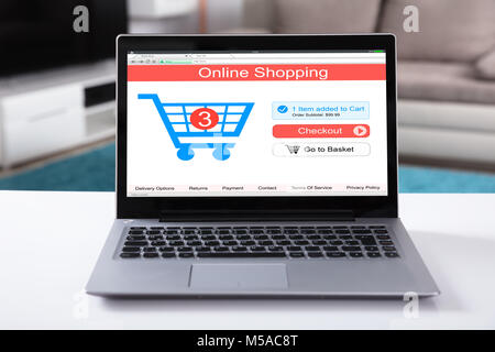 Close-up Of Online Shopping Website On Laptop Over White Desk Stock Photo