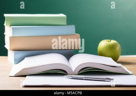 Close-up Of School Textbook On Desk In Front Of Blackboard Stock Photo