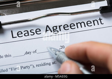Close-up Of A Human Hand Filling Lease Agreement Form With Pen Stock Photo