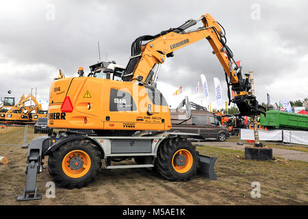 HYVINKAA, FINLAND - SEPTEMBER 8, 2017: Liebherr A 914 Compact Litronic wheeled excavator demostrates handling a birch wood log with grapple attachment Stock Photo