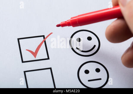 Person's Finger With Pen Over Customer Service Satisfaction Survey Form Stock Photo