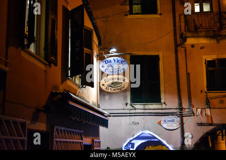 Late night in Monterosso Al Mare, Cinque Terre Italy with a colorful sign of violet and peach advertising an Italian restaurant and rooms for rent Stock Photo