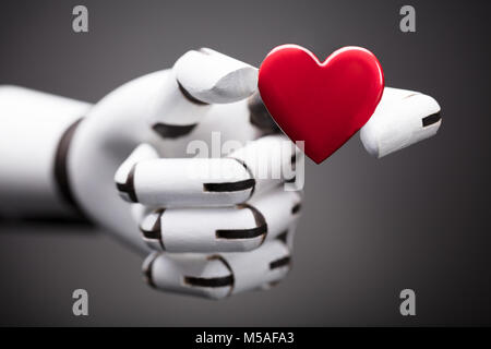 Close-up Of A Robot's Hand Holding Red Heart Stock Photo