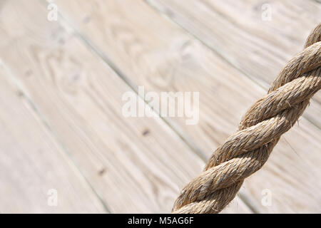 Aged rope with wooden floor boards in the background creating a natural aged texture for use as a background. Stock Photo