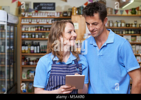 Staff In Delicatessen Using Digital Tablet Stock Photo