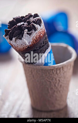 Vanilla ice cream with chocolate cookies in chocolate flavoured cone Stock Photo