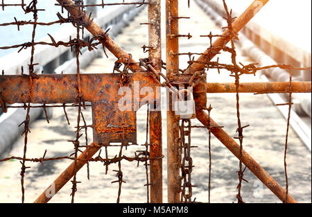 The rusty chains and old lock door in the block zone photo in sunset time warm and low lighting Stock Photo