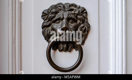 Ancient dark Doorknob in the shape of a Lion at white door Stock Photo