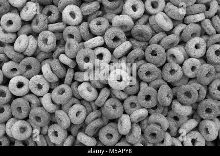 Multigrain hoops breakfast cereal - rings of wheat, barley, rice, oats and maize - as an abstract background texture - monochrome processing Stock Photo