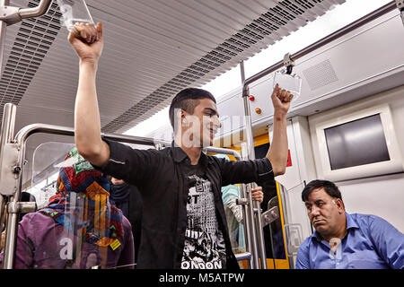 Tehran, Iran - April 29, 2017: Iranian man rides underground train and holds the rail. Stock Photo