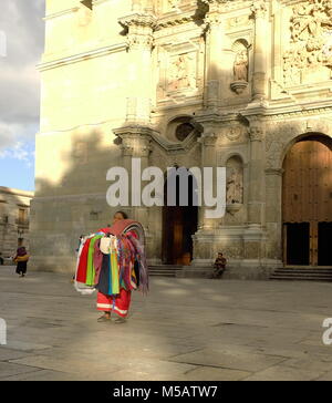 The sun sets majestically on a woman standing stoically in front of the Cathedral of Our Lady of the Assumption in Oaxaca, Mexico. Stock Photo