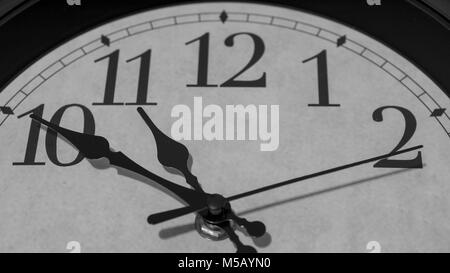 Closeup on the pointers of a clock marking ten minutes before eleven o’clock - black and white rendering Stock Photo