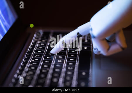 Close-up Of A Robot's Hand Typing On Laptop Stock Photo