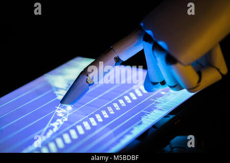Close-up Of A Robot's Hand Using Digital Tablet With Financial Graphs On Screen Stock Photo