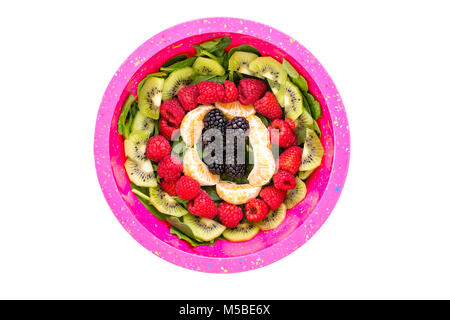 Baby spinach salad topped with fresh fruit arranged neatly in concentric circles viewed from the top with kiwi, raspberries, blackberries and segments Stock Photo