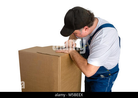 Male worker wearing dungarees opening cardboard box against white background Stock Photo