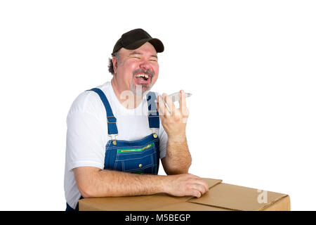 Laughing jovial worker using a speaker phone as he relaxes leaning on a large cardboard box isolated on white with copy space Stock Photo