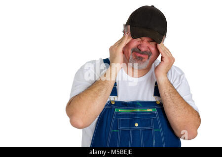 Workman in bib overalls with a migraine headache grimacing with the acute pain as he rubs his temples with his fingertips in a healthcare and medical  Stock Photo