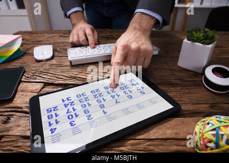 Close-up Of A Businessperson's Hand Using Calendar In Digital Tablet In Office Stock Photo