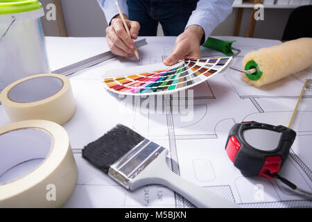 Architect's Hand Using Color Guide Swatch While Drawing Plan On Blueprint With Pencil Stock Photo