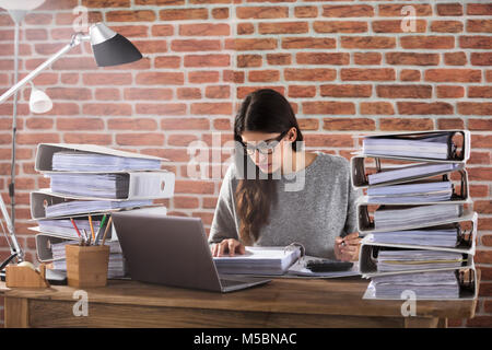 Young Businessman Working At Office With Stack Of Folders On Desk Stock Photo