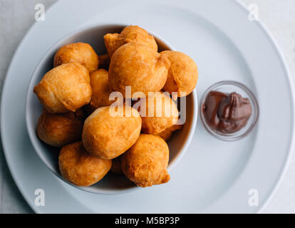 Carnival fritters or donuts or bunuelos served with cream for breakfast. Traditional serbian food - pringice. Stock Photo