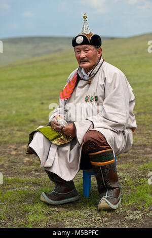Elderly male nomad in traditional dress sitting in front of his yurt ...