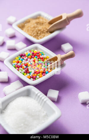 Different types of sugar with colored candy on  ceramic bowls. Useful as food background Stock Photo