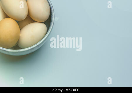 Easter bowl with eggs on blue background. Chicken egg on a blue background, free space for text. Stock Photo