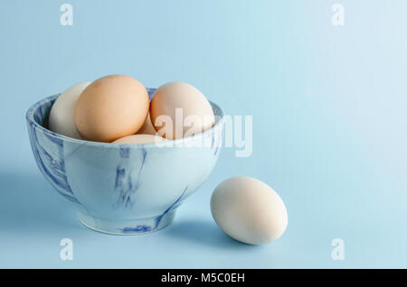 Easter bowl with eggs on blue background. Chicken egg on a blue background, free space for text. Stock Photo