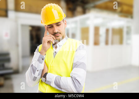 Thoughtful engineer thinking about factory problems and solutions inside the production hall Stock Photo