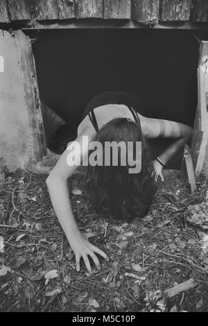 Scene of terror, girl on the floor with hair on her face crawling out of a basement Stock Photo