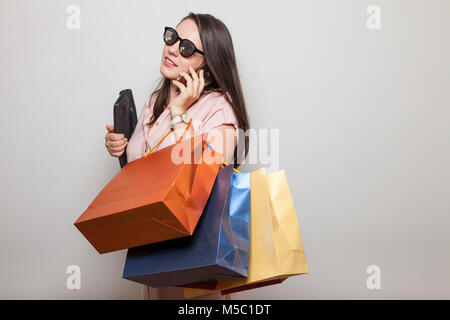 Beautiful smiling teenager talks to a phone holding gift bags Stock Photo