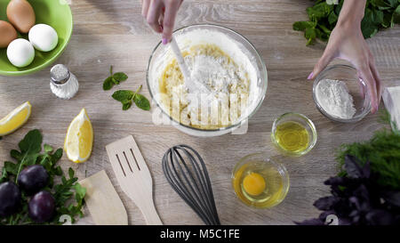 Young woman hands making dough in glass bowl, mixing baking products for pizza, stock footage Stock Photo